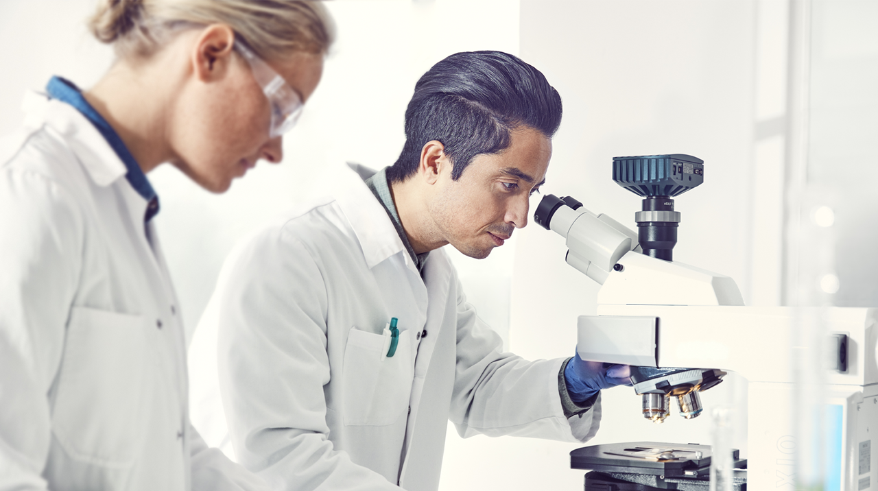 Two people looking in a microscope.