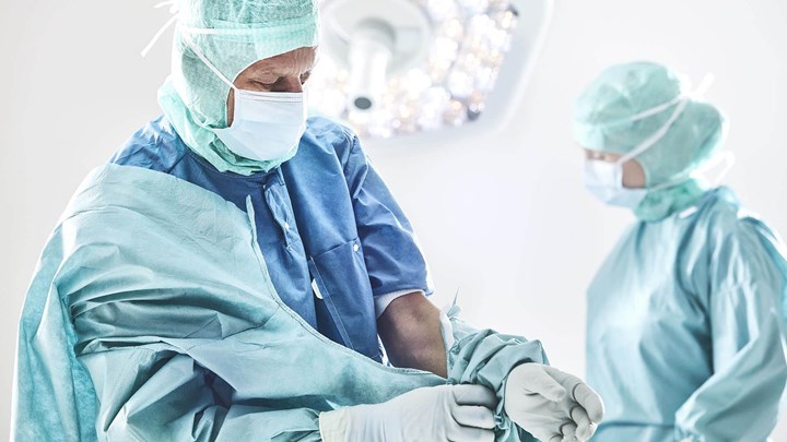 Chirurg, který si obléká plášť před operací