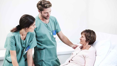 Health care professionals speaking with elderly woman