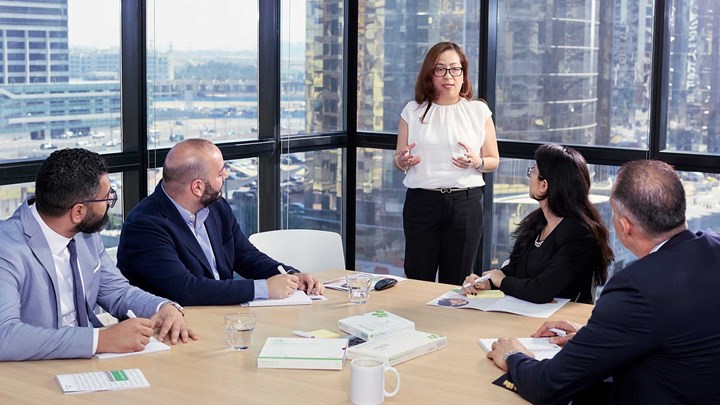 Plusieurs employés à l’écoute d’une dirigeante lors d’une réunion de bureau